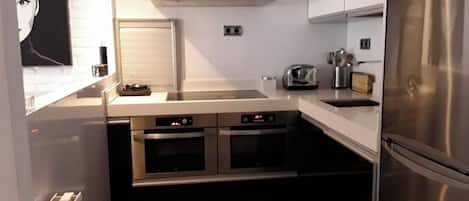 A compact kitchen with built-in appliances, including a refrigerator, oven, and microwave.
