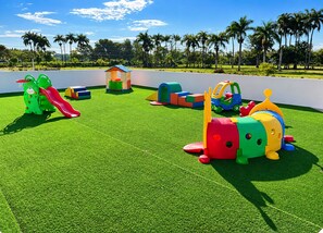 Une aire de jeux dotée de diverses structures ludiques installées sur une pelouse artificielle.