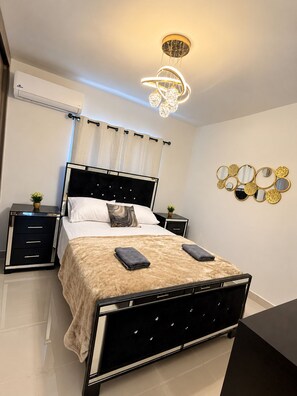 Une chambre à coucher moderne avec un cadre de lit en métal noir, du linge de lit blanc et un ensemble de miroirs décoratifs disposés sur le mur.