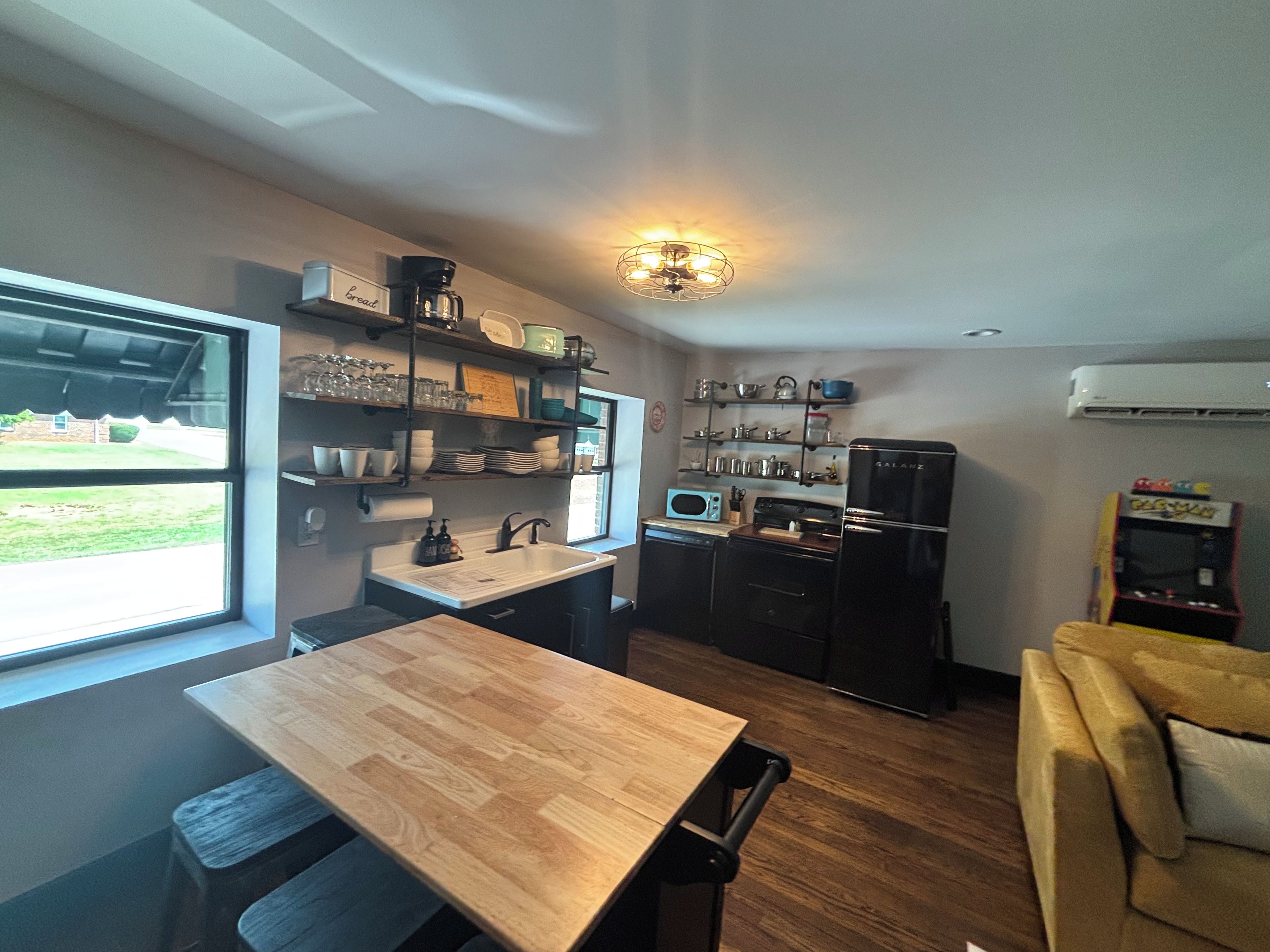 A compact kitchen with a dining table, built-in shelves, a microwave, and a refrigerator.