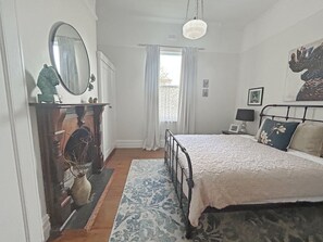 A bedroom with a bed, a dresser, a mirror, and a window with curtains. - Angelea | Coastal Haven Close to Shops & Beaches (Portland)