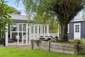 A house with a covered patio, a barbecue grill, and a large tree. - Peace and cosiness near the Limfjord (Farsø)