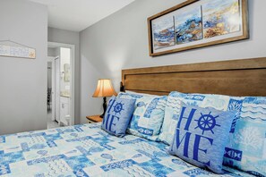 A bedroom with a bed, a nightstand, a lamp, a painting, and a sign on the wall. - Private Pool & Game Room Near Disney Parks (Kissimmee)