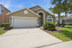 A residential house with a garage, a driveway, and a well-maintained lawn. - Private Pool & Game Room Near Disney Parks (Kissimmee)