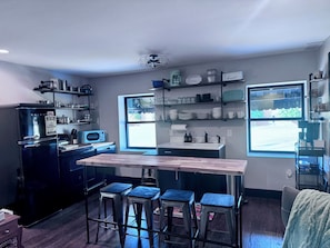 A modern kitchen with a central island, bar stools, a refrigerator, and a window with a view. - Lily's Oasis located in recently renovated historic McCoy Place Lofts. (Cave City)