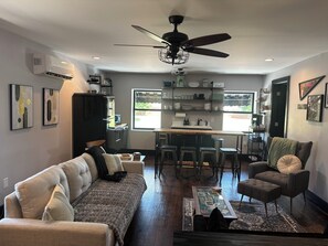 Una sala moderna con un sofá, una mesa de centro y un comedor con una cocina al fondo.