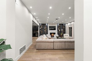 A modern living room with a sectional sofa, a fireplace, and a TV mounted on the wall. - Varna Garden House By Alora Reserve (Los Angeles)