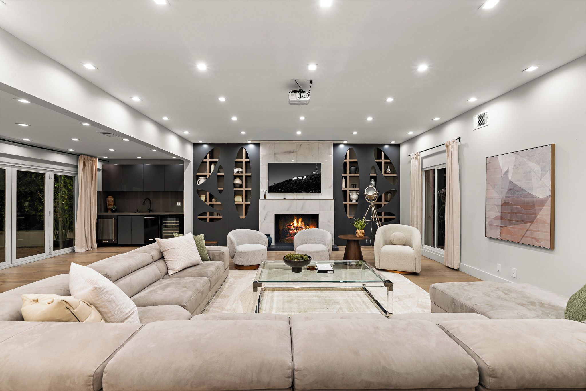 A modern living room with a sectional sofa, a glass coffee table, and a fireplace.
