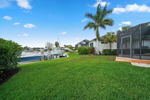 A well-maintained lawn, a boat dock, and a modern house with a glass conservatory. - Waterfront Paradise, Private Dock, 4BR, 2 bath,  Private Pool & Mins to Downtown (Punta Gorda)