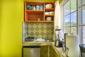 A compact kitchen with a built-in oven, a sink, and a window overlooking greenery. - Cozy Caye Caulker Apartment in Central Location w/ AC & Kitchenette | Unit 3 (Caye Caulker)