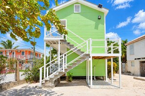 A green building with a staircase leading to a balcony. - Cozy Caye Caulker Apartment in Central Location w/ AC & Kitchenette | Unit 3 (Caye Caulker)