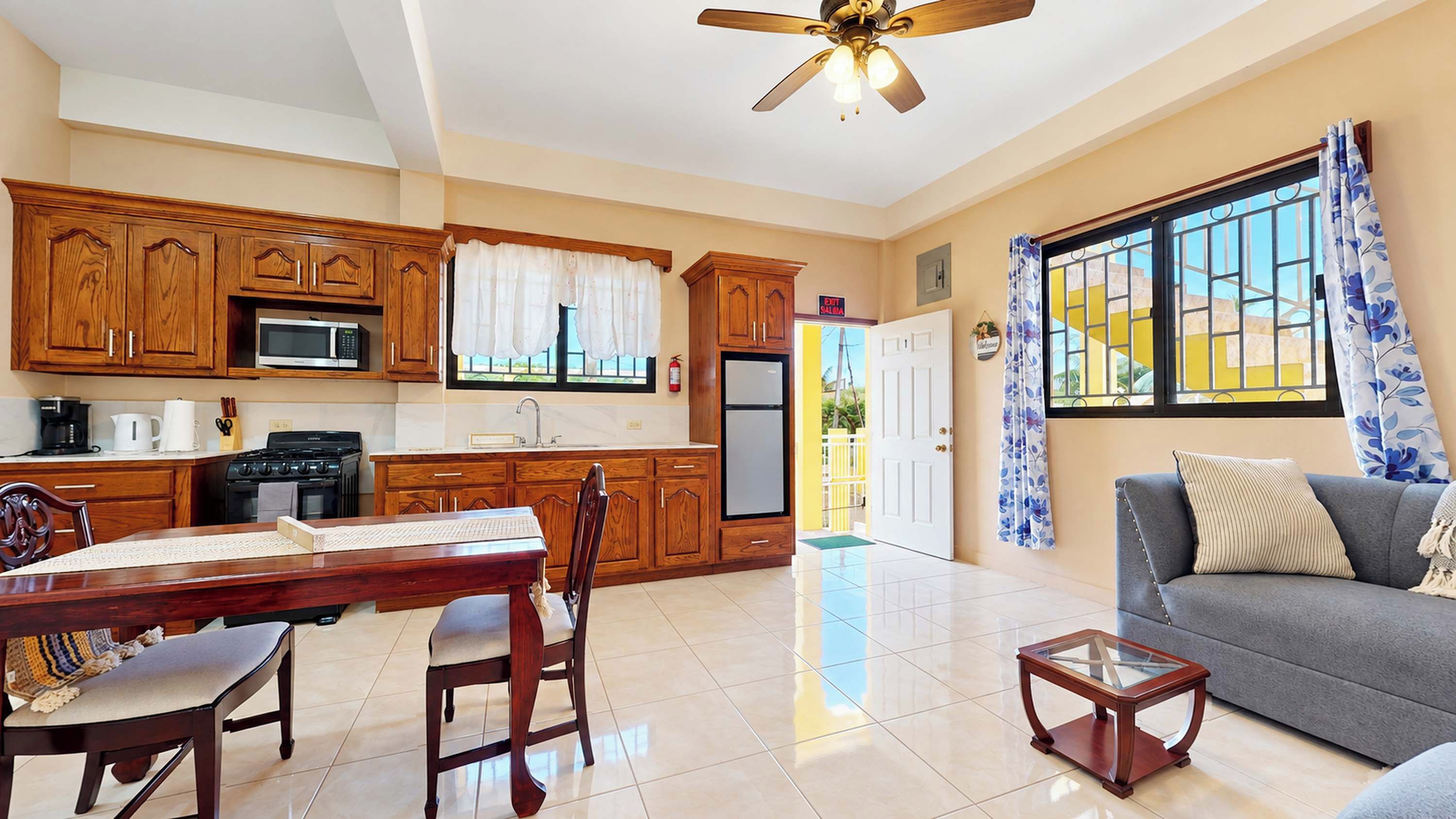 A spacious living area with a dining table, chairs, a sofa, and a glass coffee table.
