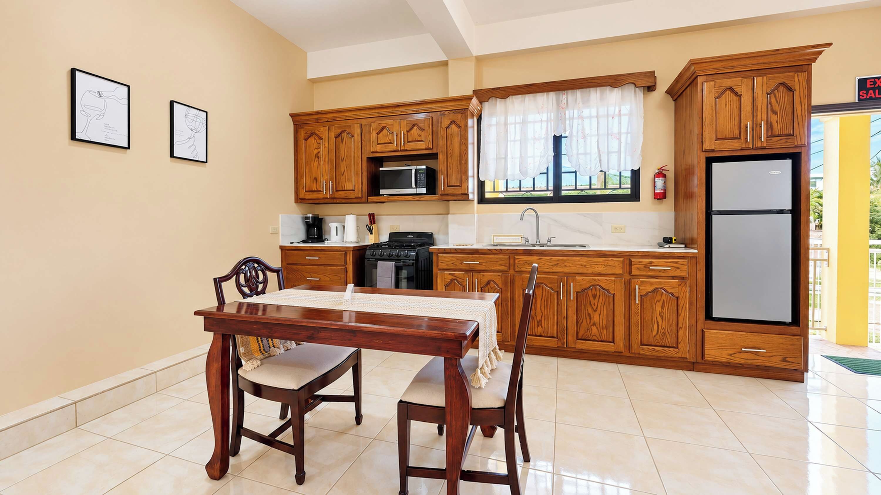 A kitchen with wooden cabinets, a dining table with chairs, a microwave, a stove, and a refrigerator.