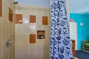 A bathroom with a shower, tiled walls, a showerhead, and a curtain with an underwater theme. - Central Caye Caulker Apartment w/ AC, Wi-Fi & Kitchen | Unit 2 (Caye Caulker)