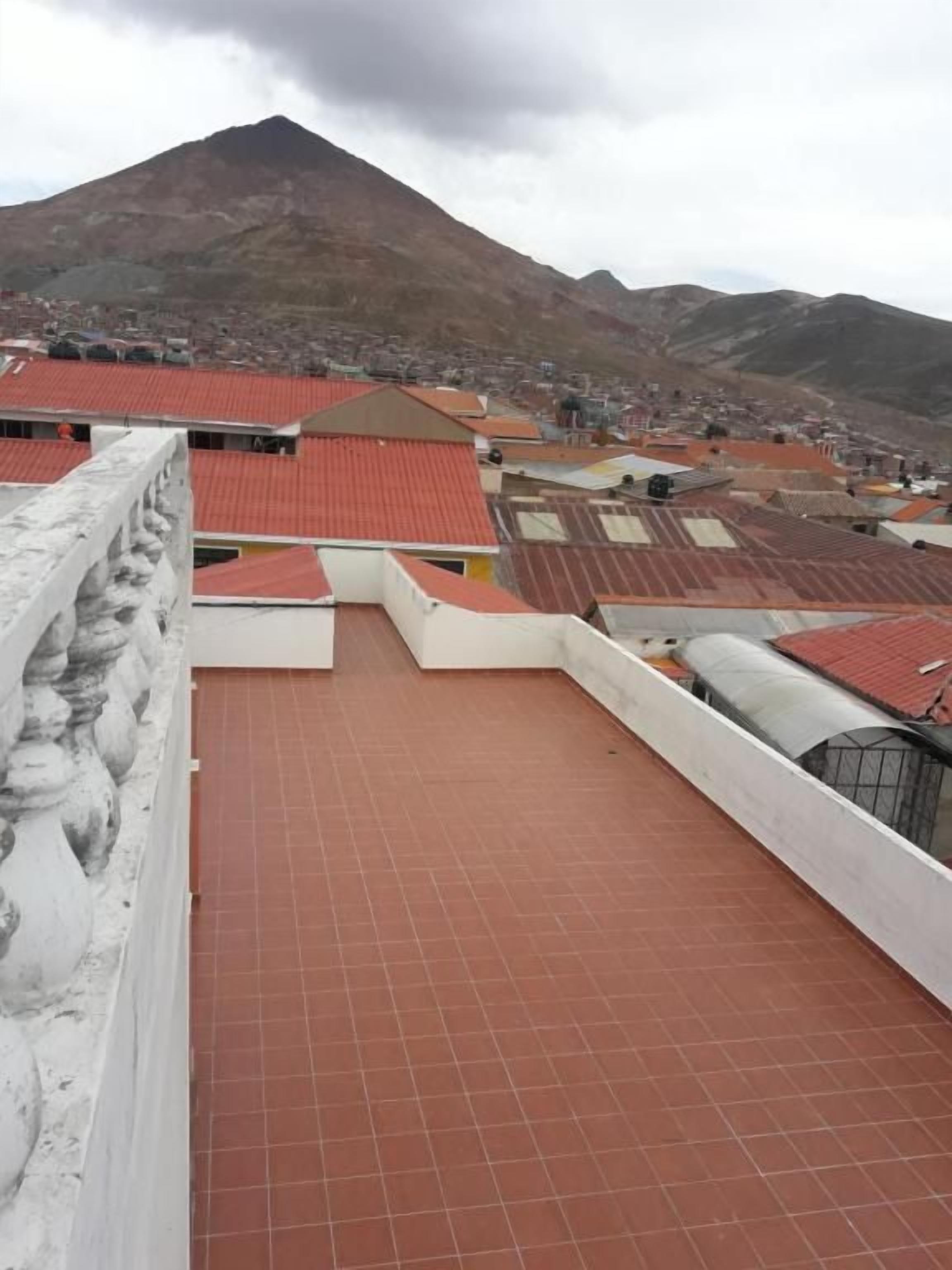 A rooftop terrace with a tiled floor and a view of a mountain in the background.