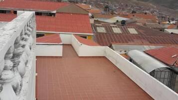 A rooftop terrace with a tiled floor and a view of a mountain in the background.