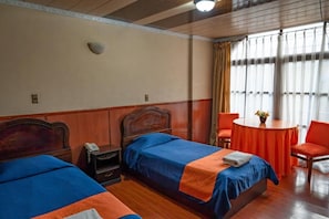 A hotel room with two beds, a small table with chairs, and a window with curtains. - Tukos La Casa Real (Potosi)