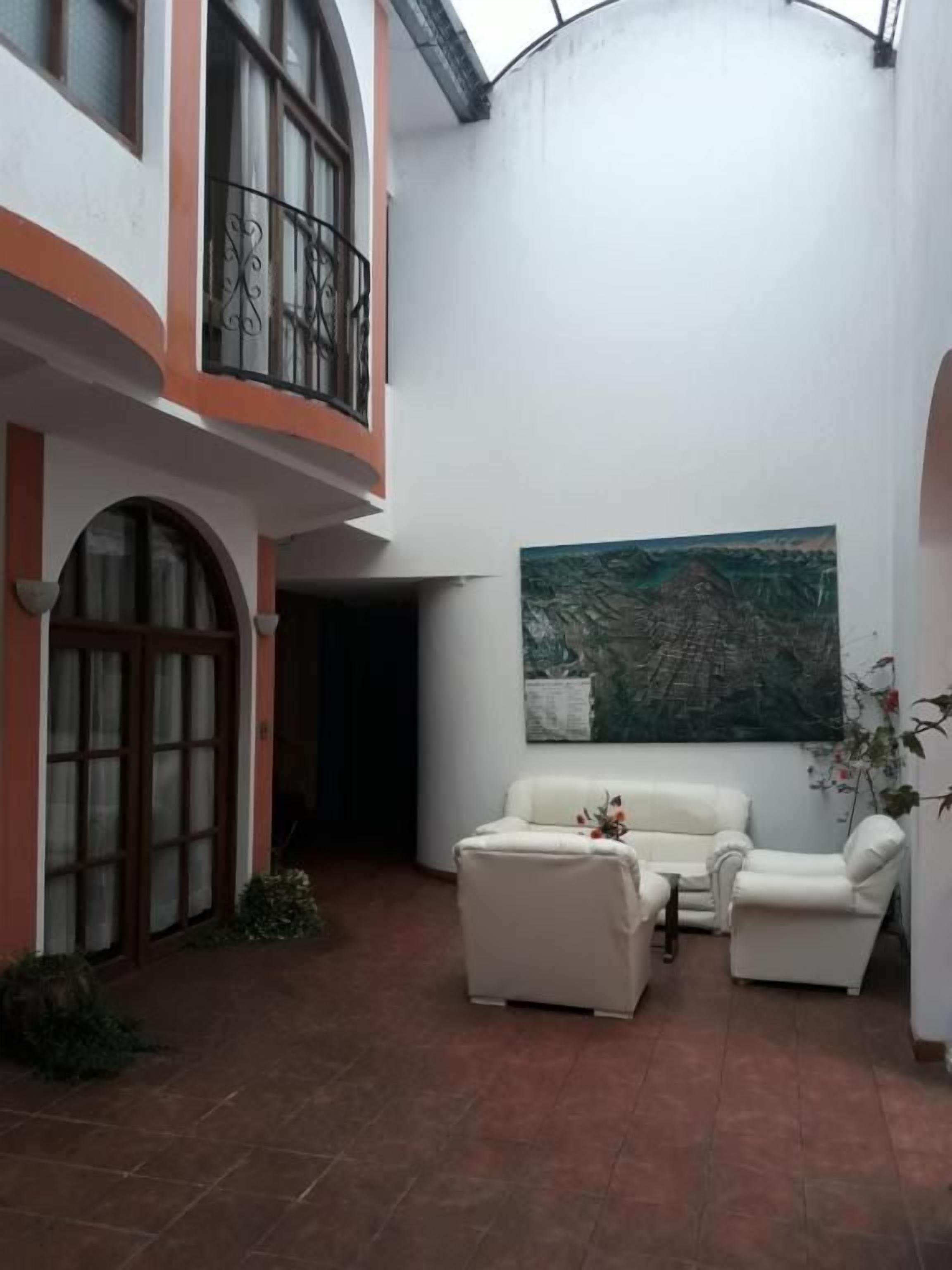 A courtyard with a white sofa, a painting, and a potted plant.
