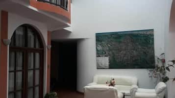 A courtyard with a white sofa, a painting, and a potted plant.