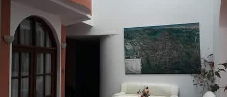 A courtyard with a white sofa, a painting, and a potted plant.