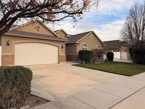 A residential house with a garage, a well-maintained lawn, and a clear sky. - Modern Retreat, Cozy, Calm & Perfectly Located (West Jordan)