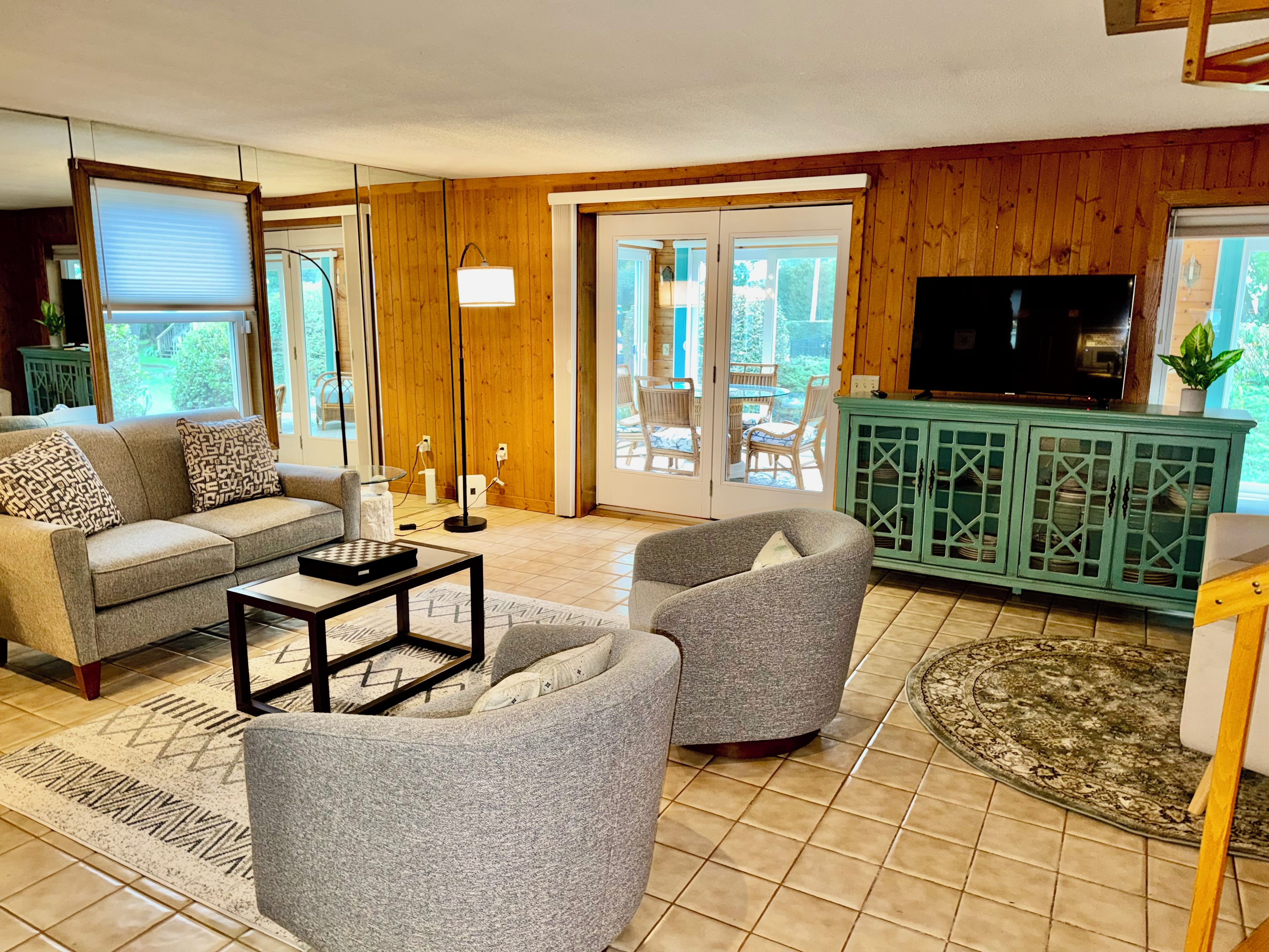 A living room with a sofa, armchair, coffee table, and a television.