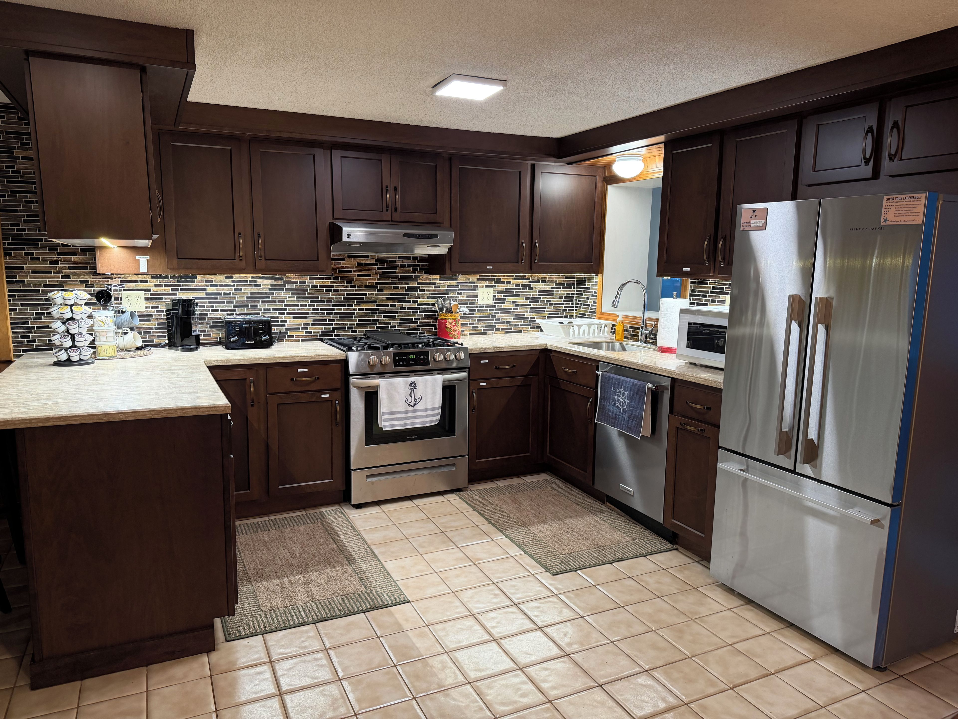 A modern kitchen with dark wood cabinets, a stainless steel refrigerator, and a tiled backsplash.