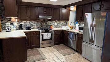 A modern kitchen with dark wood cabinets, a stainless steel refrigerator, and a tiled backsplash.