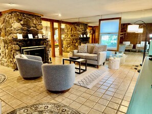 Una sala de estar con paredes de piedra, una chimenea y un área de descanso con un sofá y sillones.