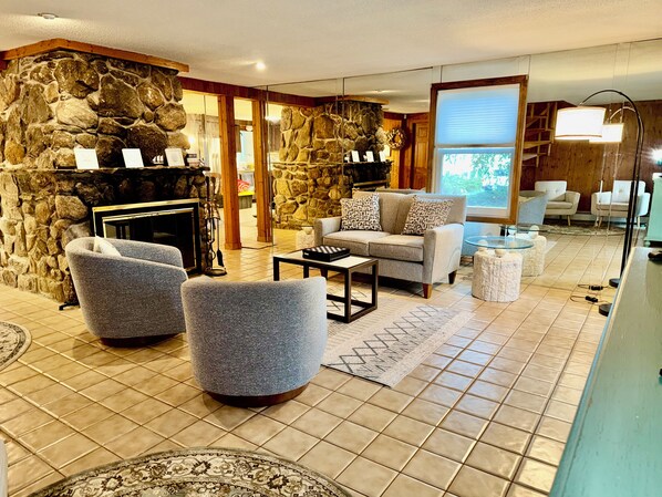 A living room with stone walls, a fireplace, and a seating area with a sofa and armchairs.