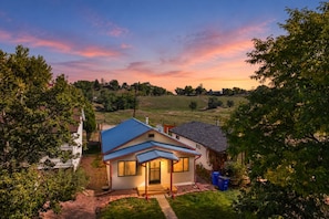 A house with a blue roof, surrounded by greenery and a clear sky. - Westside Bungalow | King Bed + Fenced Yard + Pets! (Colorado Springs)