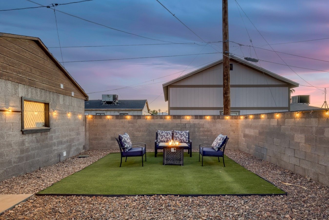 Un jardin avec un foyer, deux chaises et une table.