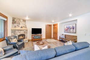 Ein Wohnzimmer mit Kamin aus Stein, einem Fernseher, einer Couch und einem Gemälde an der Wand.