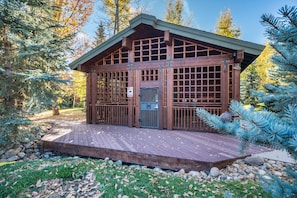 Eine Holzhütte mit einer Veranda, umgeben von Bäumen und Felsen.
