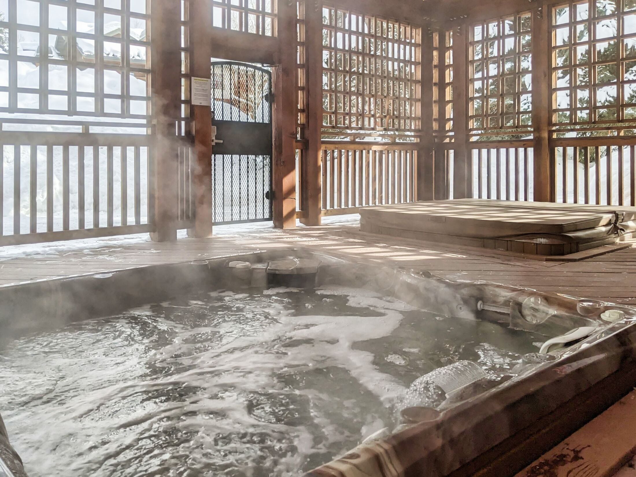 A hot spring area with a wooden deck and a view of the outside.