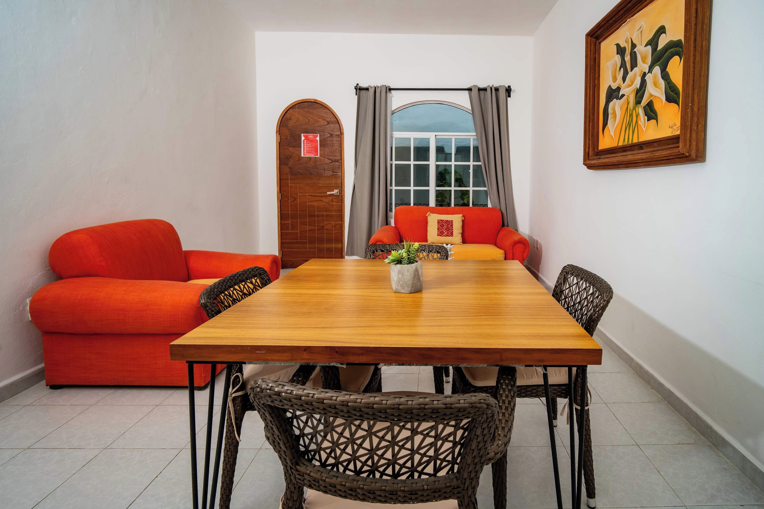 Een eetgedeelte met een houten tafel, rieten stoelen en twee rode banken.