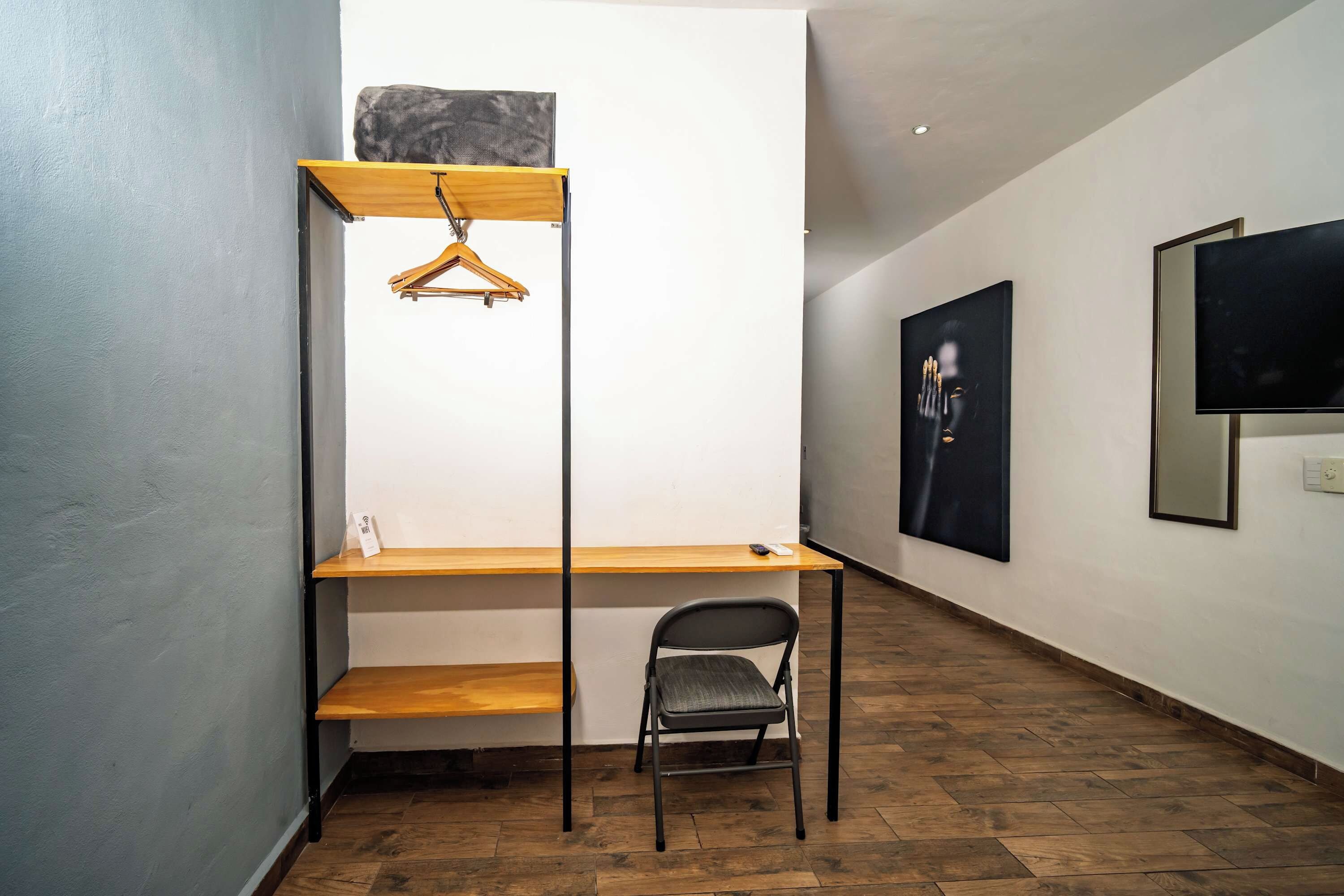 A room with a wooden desk, a chair, and a hanging garment rack.