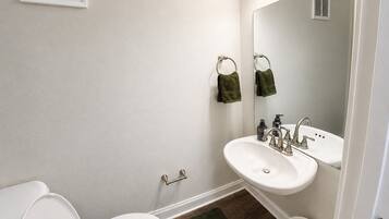 Un baño con inodoro, lavamanos y espejo.