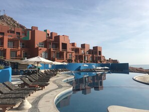 Een resort met een zwembad, ligbedden en uitzicht op de oceaan.