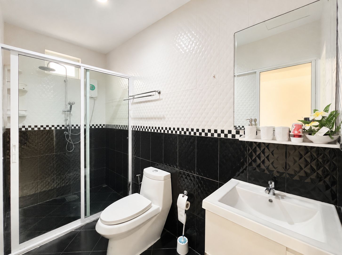 A modern bathroom with a glass shower enclosure, a toilet, a sink, and a mirror.