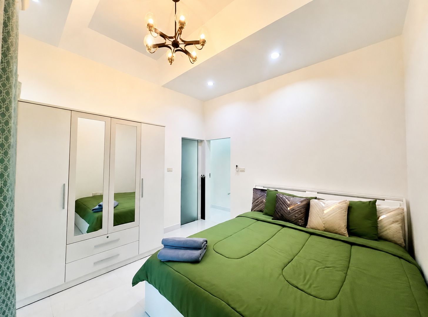 A bedroom with a bed, a wardrobe, a mirror, and a chandelier.