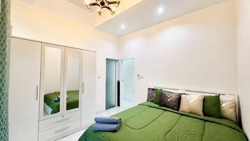 A bedroom with a bed, a wardrobe, a mirror, and a chandelier.