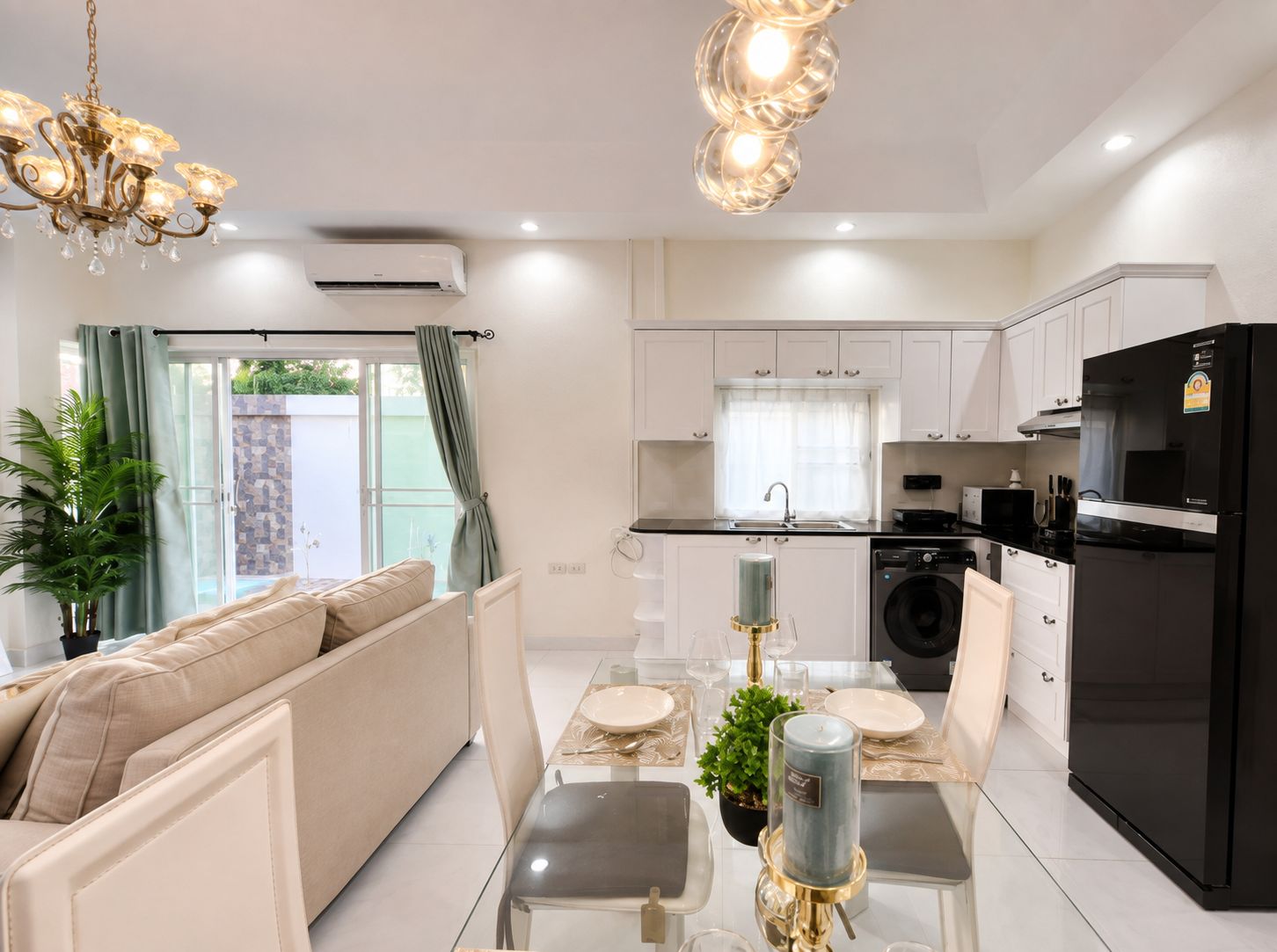 A modern kitchen with white cabinets, a black refrigerator, and a dining area with a glass table and chairs.