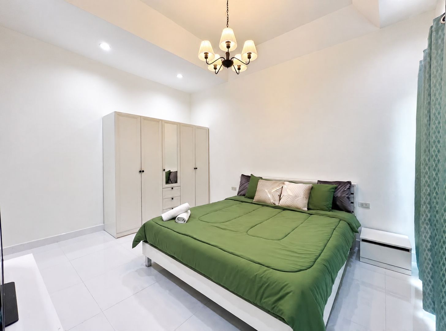 A bedroom with a bed, a wardrobe, and a ceiling light fixture.