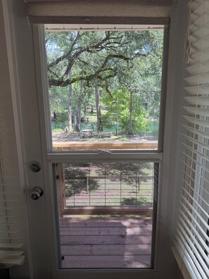 A door with a view of a wooded area, a bench, and a fenced outdoor space. - Rivendell Springs River Home: 12 Private Acres on Santa Fe River near Springs (High Springs)