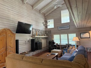 A spacious living room with a fireplace, a television, and a comfortable seating area. - Rivendell Springs River Home: 12 Private Acres on Santa Fe River near Springs (High Springs)