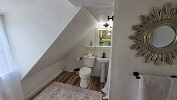 Een badkamer met toilet, wastafel en spiegel.