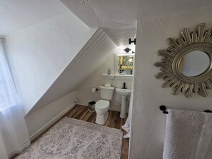 Een badkamer met toilet, wastafel en spiegel.