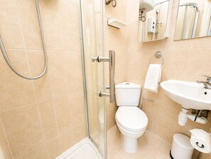 A modern bathroom with a glass-enclosed shower, a toilet, a sink, and a toilet paper holder. - Islington Gem Studio near Angel and Highbury (London)