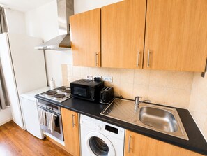 A compact kitchen with a microwave, toaster, sink, oven, and washing machine. - Islington Gem Studio near Angel and Highbury (London)